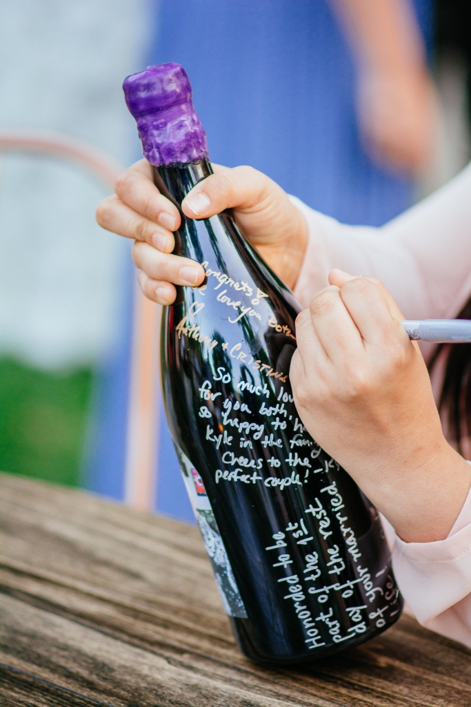 wedding guests signing a wine bottle guest book