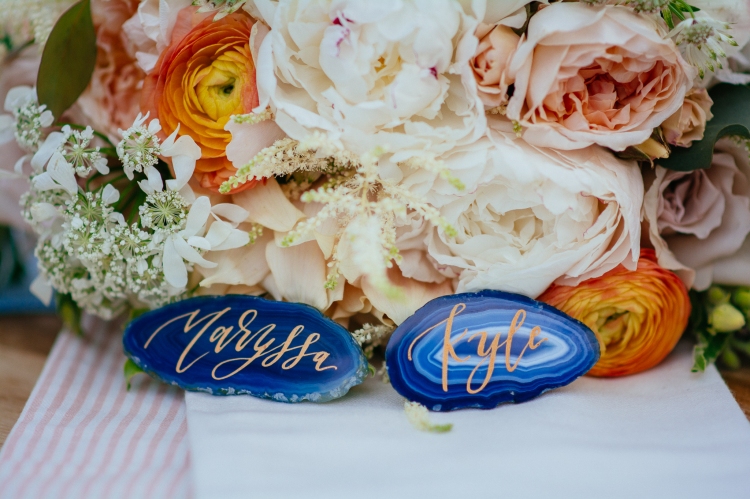 bride and groom blue stone agate name plates in front of flower bouquet